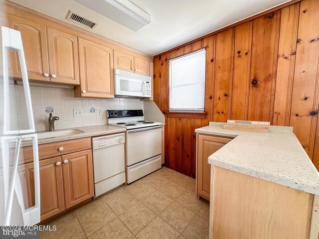 kitchen with light stone counters, sink, tasteful backsplash, white appliances, and light brown cabinetry