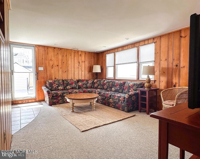 carpeted living room featuring wood walls