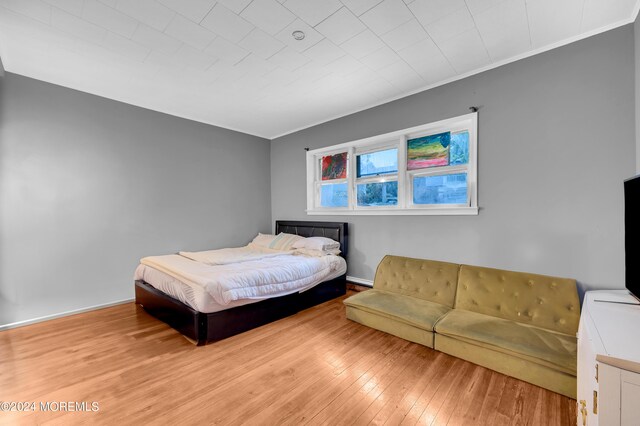 bedroom featuring light wood-type flooring and crown molding