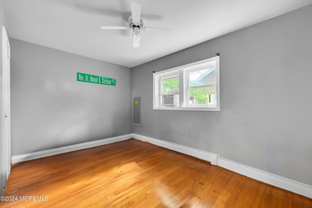 empty room featuring ceiling fan, electric panel, and wood-type flooring