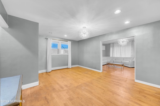 spare room with a chandelier and light hardwood / wood-style floors