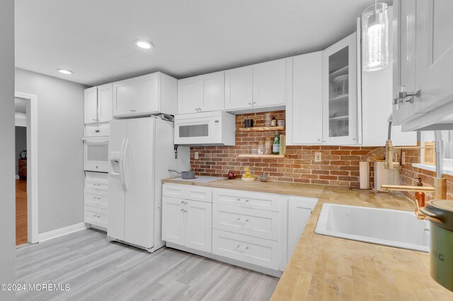 kitchen with hanging light fixtures, white cabinetry, tasteful backsplash, white appliances, and light hardwood / wood-style flooring