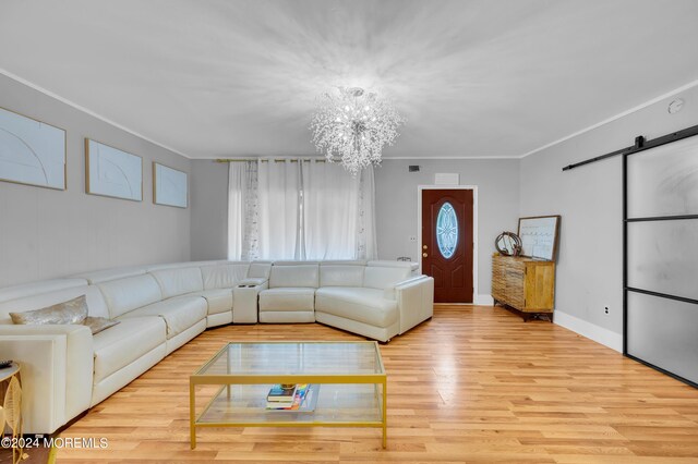 living room featuring light hardwood / wood-style flooring, a chandelier, crown molding, and a barn door