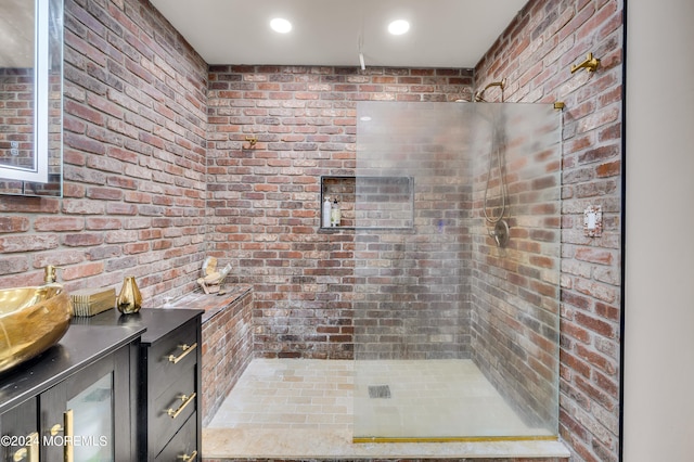 bathroom with a shower, vanity, and brick wall