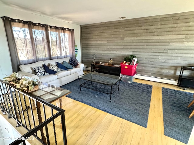 living room featuring baseboard heating, wood walls, and hardwood / wood-style flooring