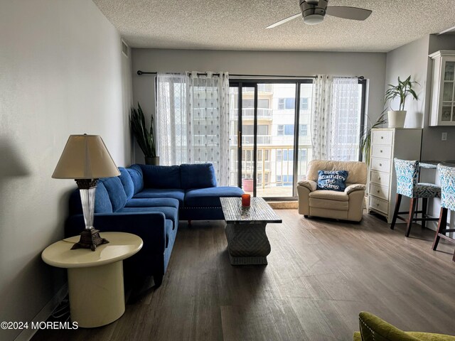 living room with a textured ceiling, dark hardwood / wood-style floors, and ceiling fan