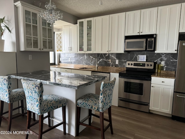 kitchen featuring decorative light fixtures, stainless steel appliances, and white cabinets