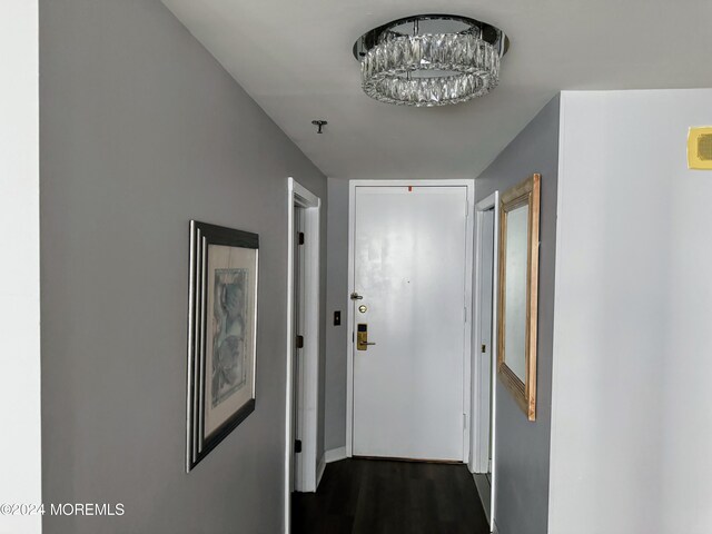 corridor featuring an inviting chandelier and dark hardwood / wood-style flooring