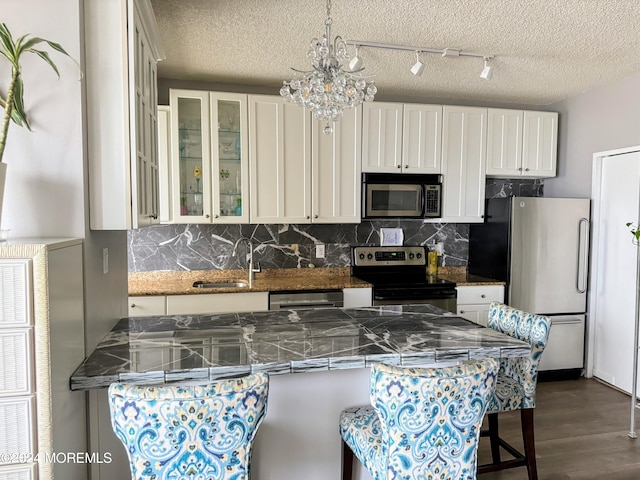 kitchen with a breakfast bar, stainless steel appliances, white cabinetry, and sink