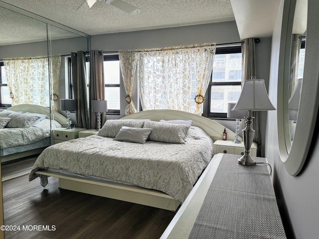 bedroom with a textured ceiling, ceiling fan, and dark hardwood / wood-style flooring