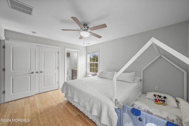 bedroom with wood-type flooring, a closet, ensuite bath, and ceiling fan