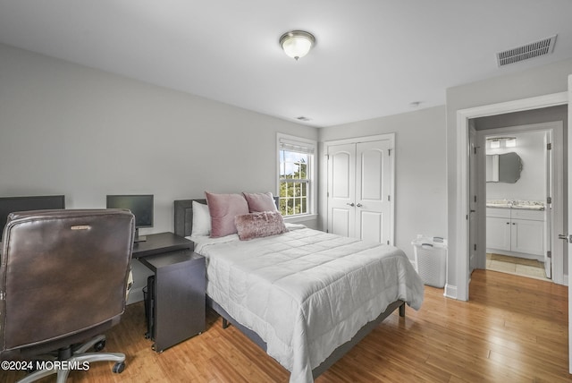 bedroom featuring a closet, ensuite bath, and light hardwood / wood-style floors