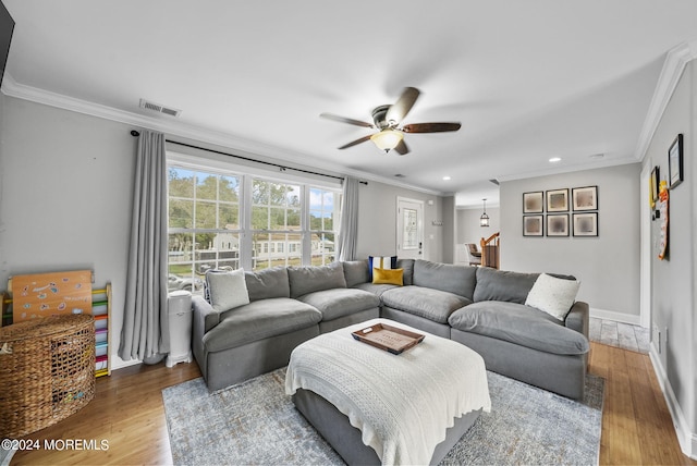 living room featuring wood-type flooring, ornamental molding, and ceiling fan