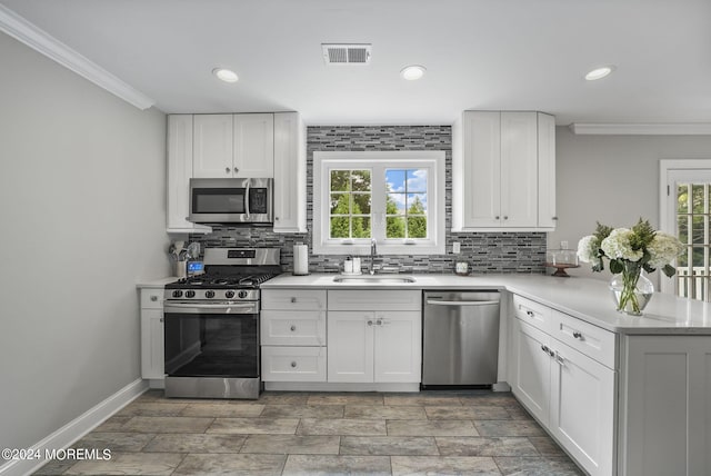 kitchen with appliances with stainless steel finishes, crown molding, sink, and white cabinets