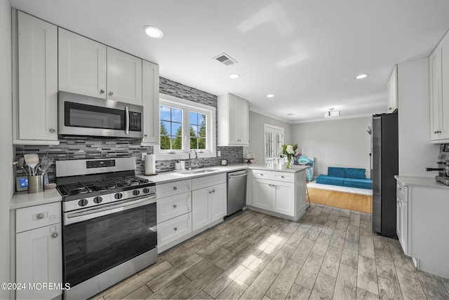 kitchen featuring white cabinets, sink, kitchen peninsula, hardwood / wood-style flooring, and stainless steel appliances