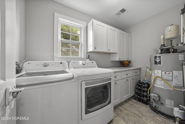 clothes washing area featuring light hardwood / wood-style floors, separate washer and dryer, gas water heater, and cabinets