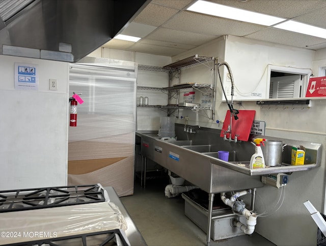 kitchen with concrete flooring, a drop ceiling, and range with gas cooktop