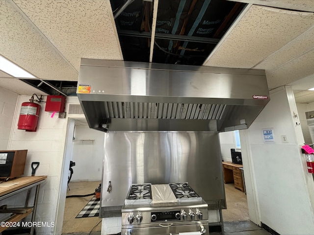 kitchen featuring stainless steel range, wall chimney exhaust hood, and a paneled ceiling