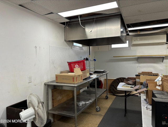 basement featuring a healthy amount of sunlight, a drop ceiling, and a wall unit AC