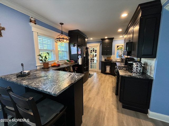 kitchen featuring pendant lighting, black appliances, light wood-type flooring, crown molding, and decorative backsplash