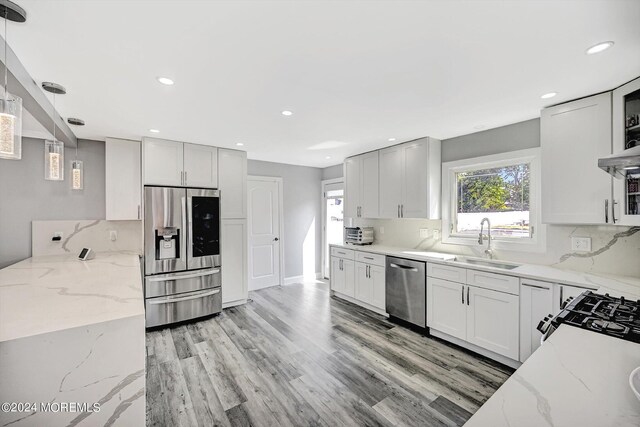 kitchen featuring light stone counters, stainless steel appliances, sink, and white cabinetry