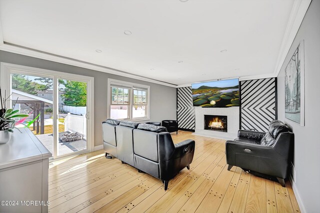 living room with light wood-type flooring, ornamental molding, and plenty of natural light