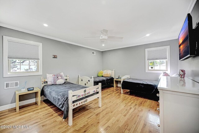 bedroom with ceiling fan, light wood-type flooring, ornamental molding, and multiple windows