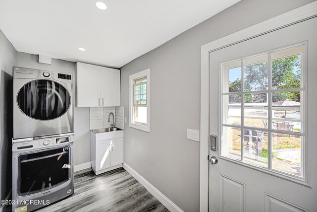 laundry room with cabinets, stacked washer / dryer, dark wood-type flooring, and a wealth of natural light