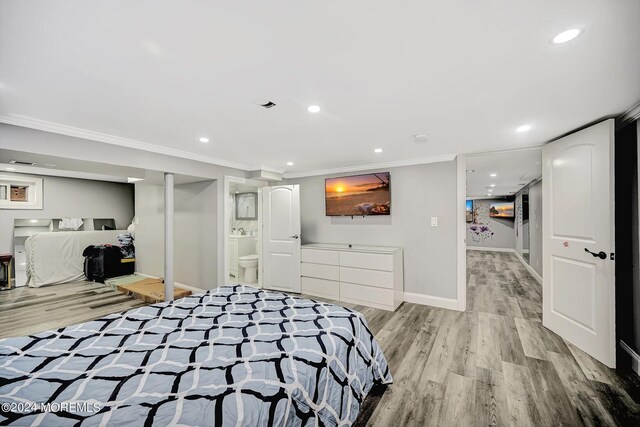 bedroom featuring a closet, light hardwood / wood-style floors, crown molding, and ensuite bathroom