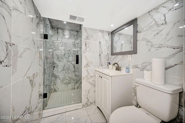 bathroom with tile walls, vanity, toilet, and an enclosed shower