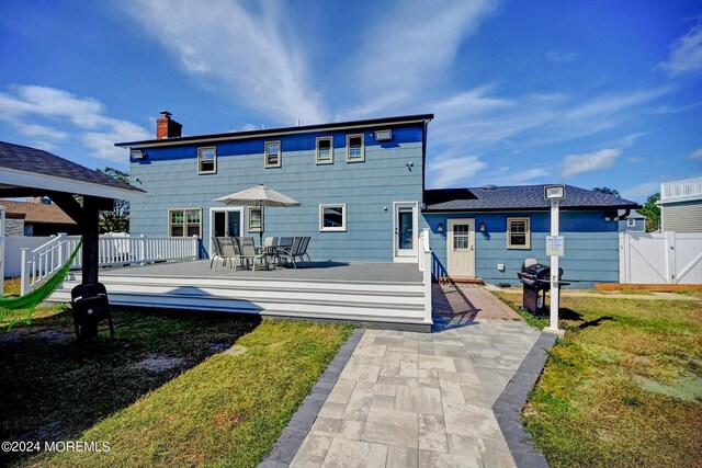 back of property with a wooden deck and a lawn