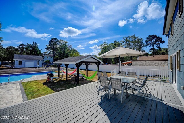 deck featuring a gazebo, a fenced in pool, and an outdoor structure