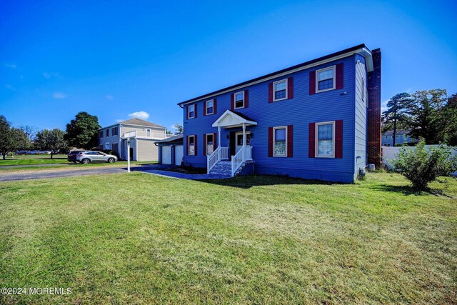 colonial inspired home featuring a garage and a front lawn