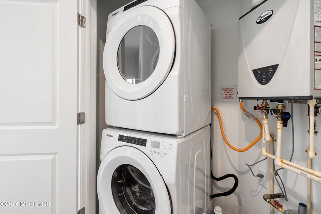 laundry room with water heater and stacked washer / dryer