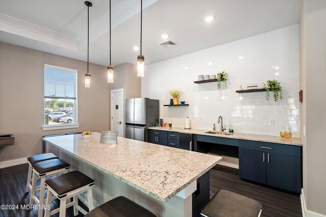 kitchen featuring a breakfast bar area, stainless steel fridge, dark hardwood / wood-style flooring, and sink