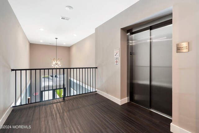 hallway with a notable chandelier, dark hardwood / wood-style floors, and elevator