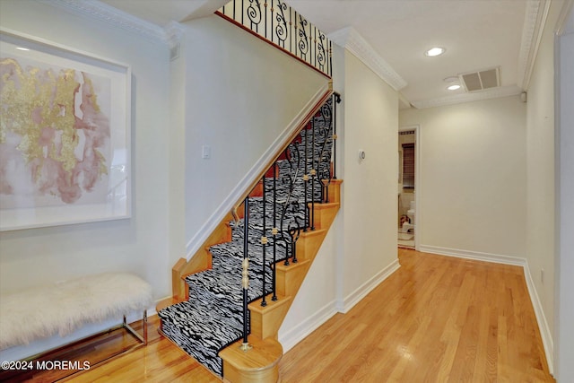 stairs featuring wood-type flooring and ornamental molding