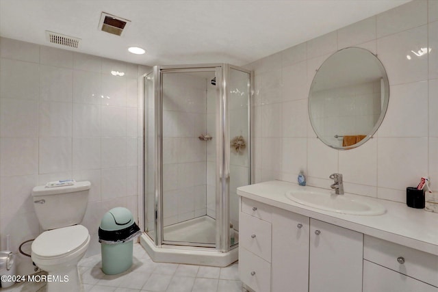 bathroom with tile walls, tile patterned flooring, an enclosed shower, vanity, and toilet