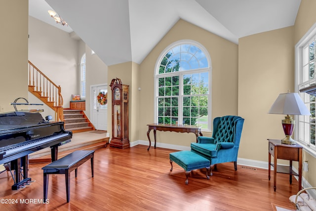 living area with light hardwood / wood-style floors, lofted ceiling, and a wealth of natural light