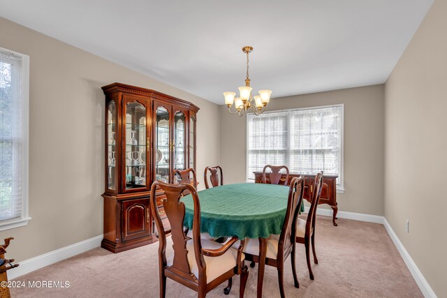 dining area with an inviting chandelier, light colored carpet, and a wealth of natural light