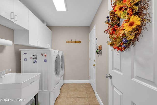 clothes washing area featuring washer and clothes dryer, sink, light tile patterned floors, and cabinets