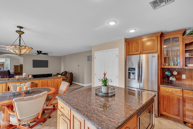 kitchen featuring ceiling fan, hanging light fixtures, light tile patterned floors, a kitchen island, and stainless steel appliances