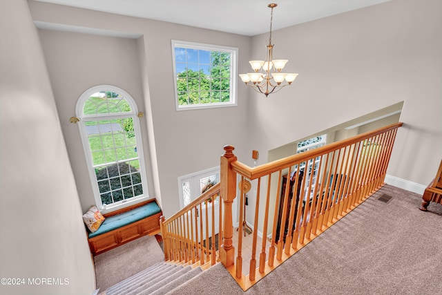 stairs with carpet, a high ceiling, and a chandelier