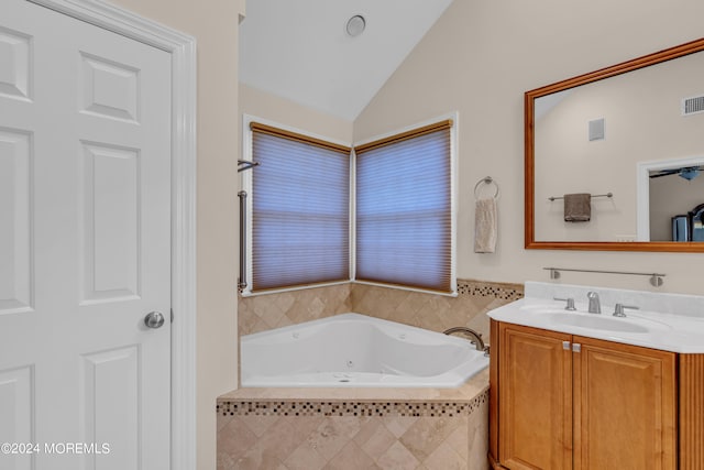 bathroom with lofted ceiling, tiled tub, and vanity