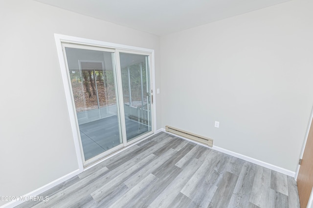 spare room with a baseboard radiator, wood finished floors, and baseboards