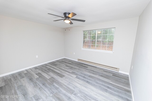 unfurnished room featuring ceiling fan, light wood-type flooring, and a baseboard heating unit