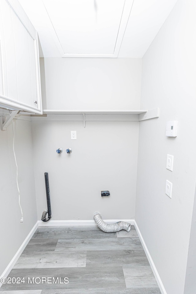 laundry area with attic access, cabinet space, baseboards, and light wood-style floors