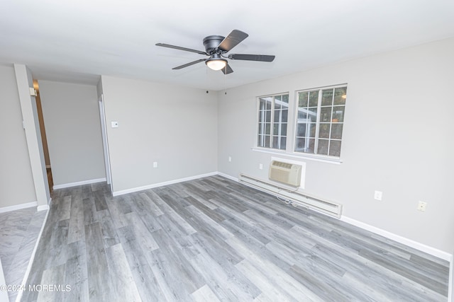 spare room with ceiling fan, an AC wall unit, light wood-type flooring, and a baseboard radiator