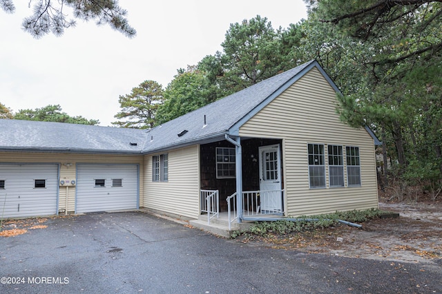 view of front of home with driveway, a shingled roof, and an attached garage