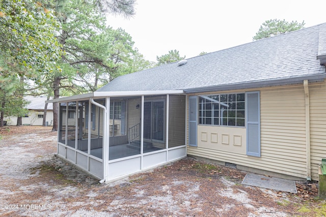 back of house with roof with shingles and a sunroom